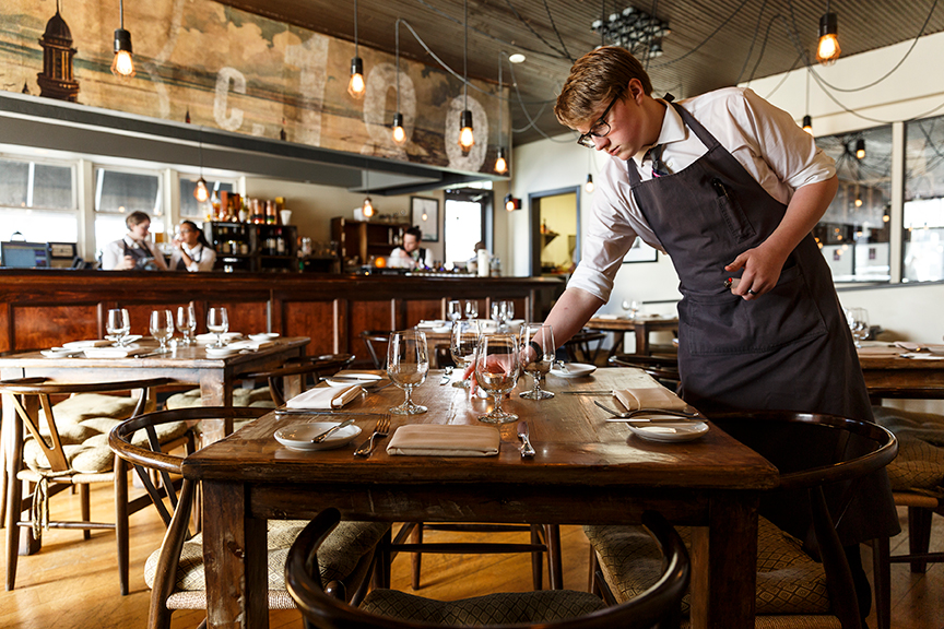 food photographer Milwaukee - a server sets a table at a high end restaurant 