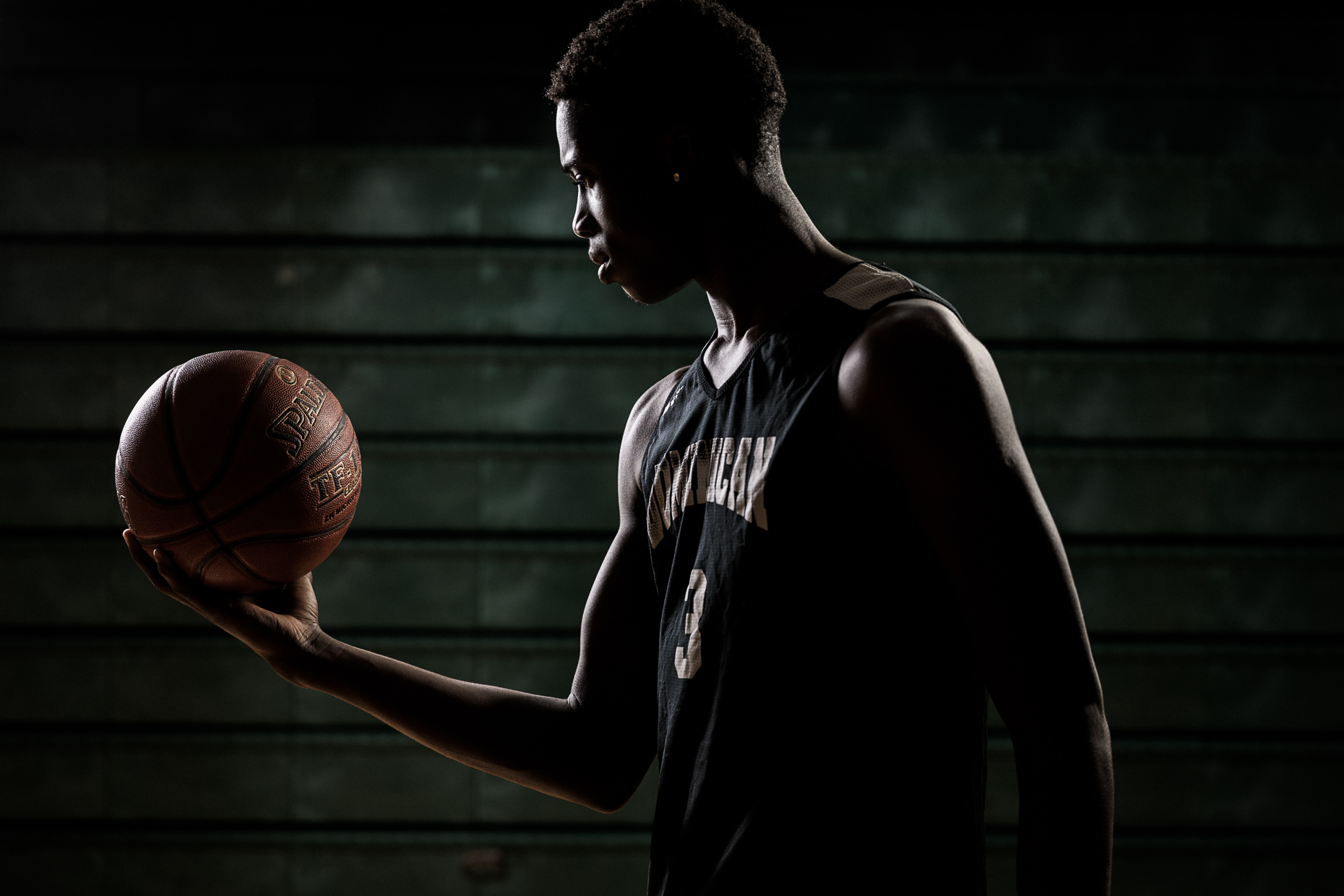 editorial sports photographer - Alex Antetokounmpo holding a basketball at his high school gym