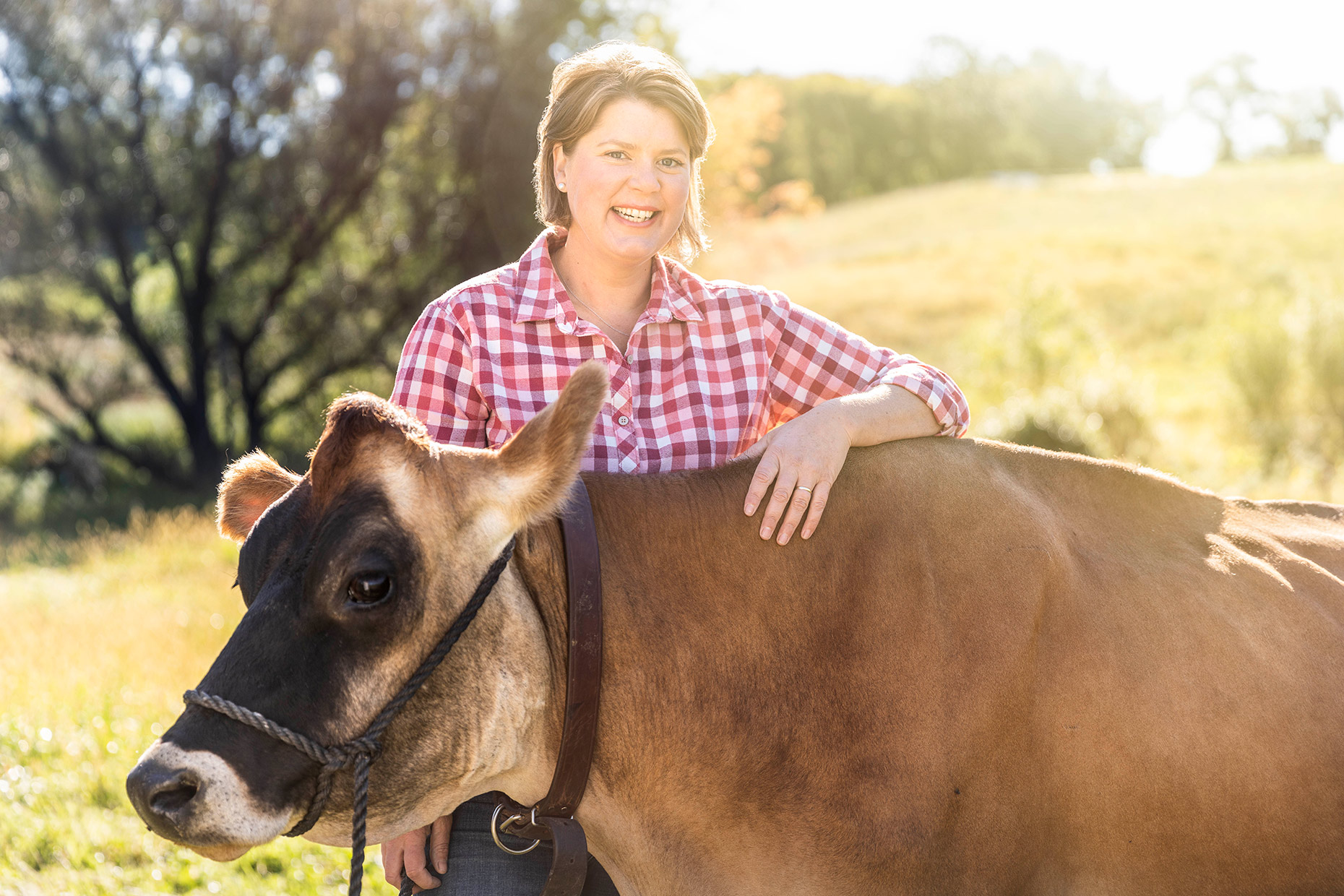 Wisconsin agriculture photographer - Inga Orth, host of PBS show, Around the Farm Table, stands in the field with a dairy cow