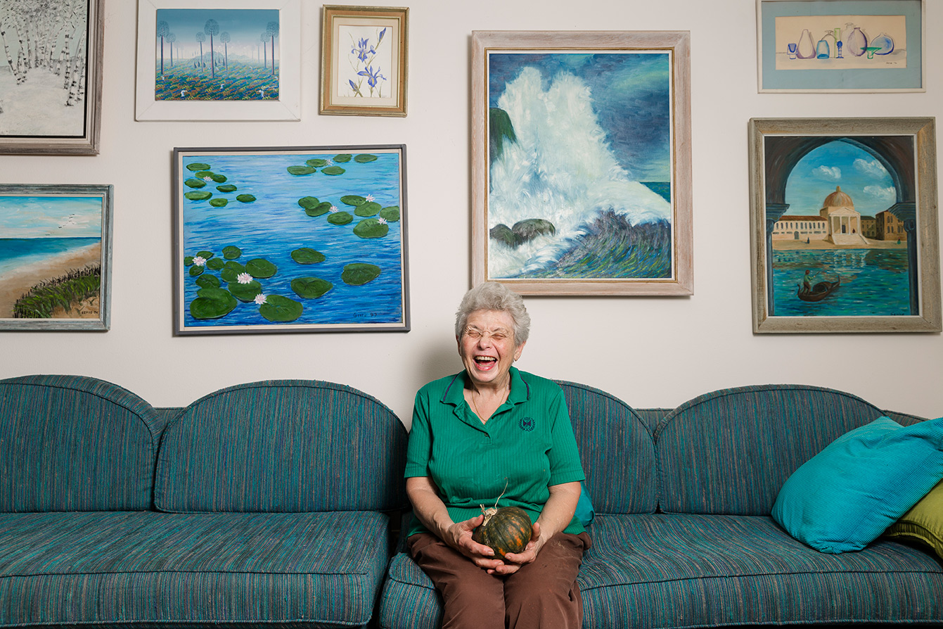 editorial photographer - an elderly woman sitting on a couch is laughing