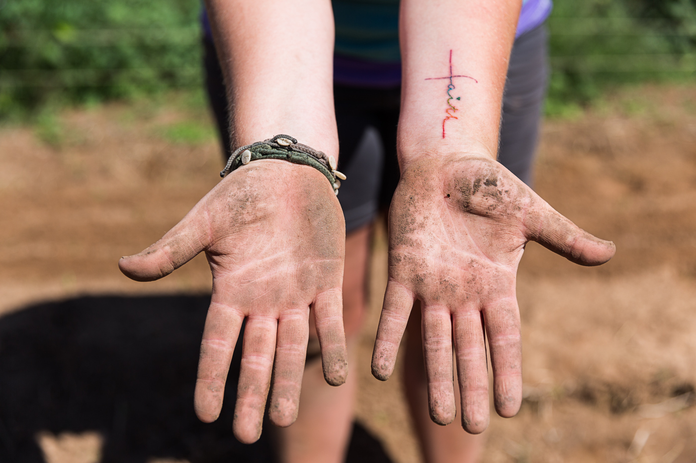 farm photographer - a farmer shows off her dirty hands after pulling weeds at Hell