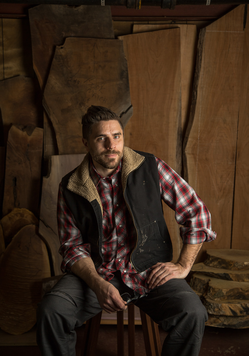 commercial photographer Midwest - a furniture maker sits in front of a large piece of wood