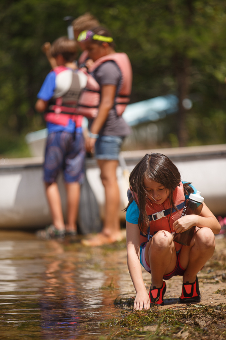 commercial photographer Midwest - a girl knelling reaches into the water at summer camp