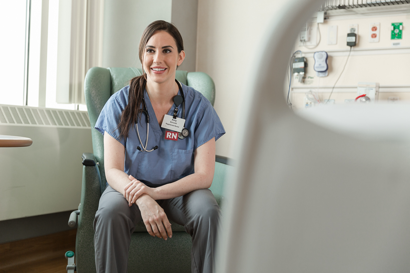 healthcare photographer Milwaukee - a nurse at an Aurora hospital sits on a chair in a hospital room